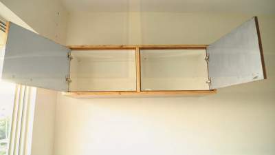 How do you secure a storage cabinet to the wall?